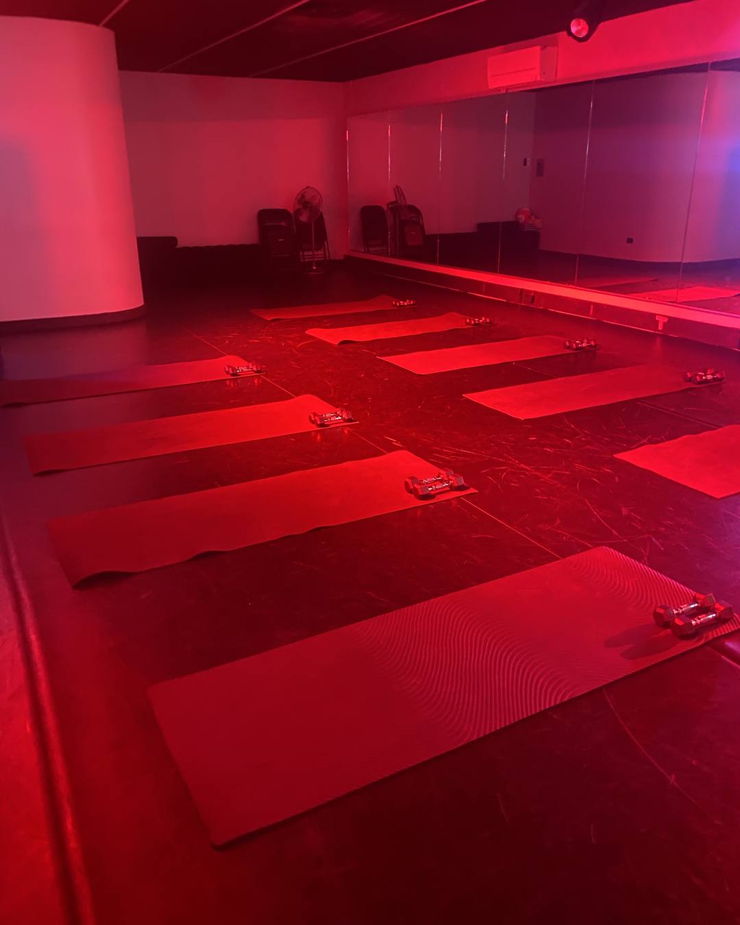 Red-lit studio at Kinetic Studio, Ashfield, with mats and dumbbells set out in rows